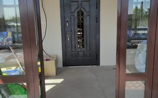 парадная дверь со стеклом и кованой решеткой арочного типа для загородного дома